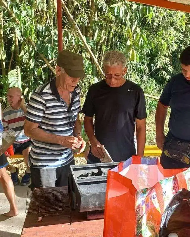 Group gathered around a grill under a shed